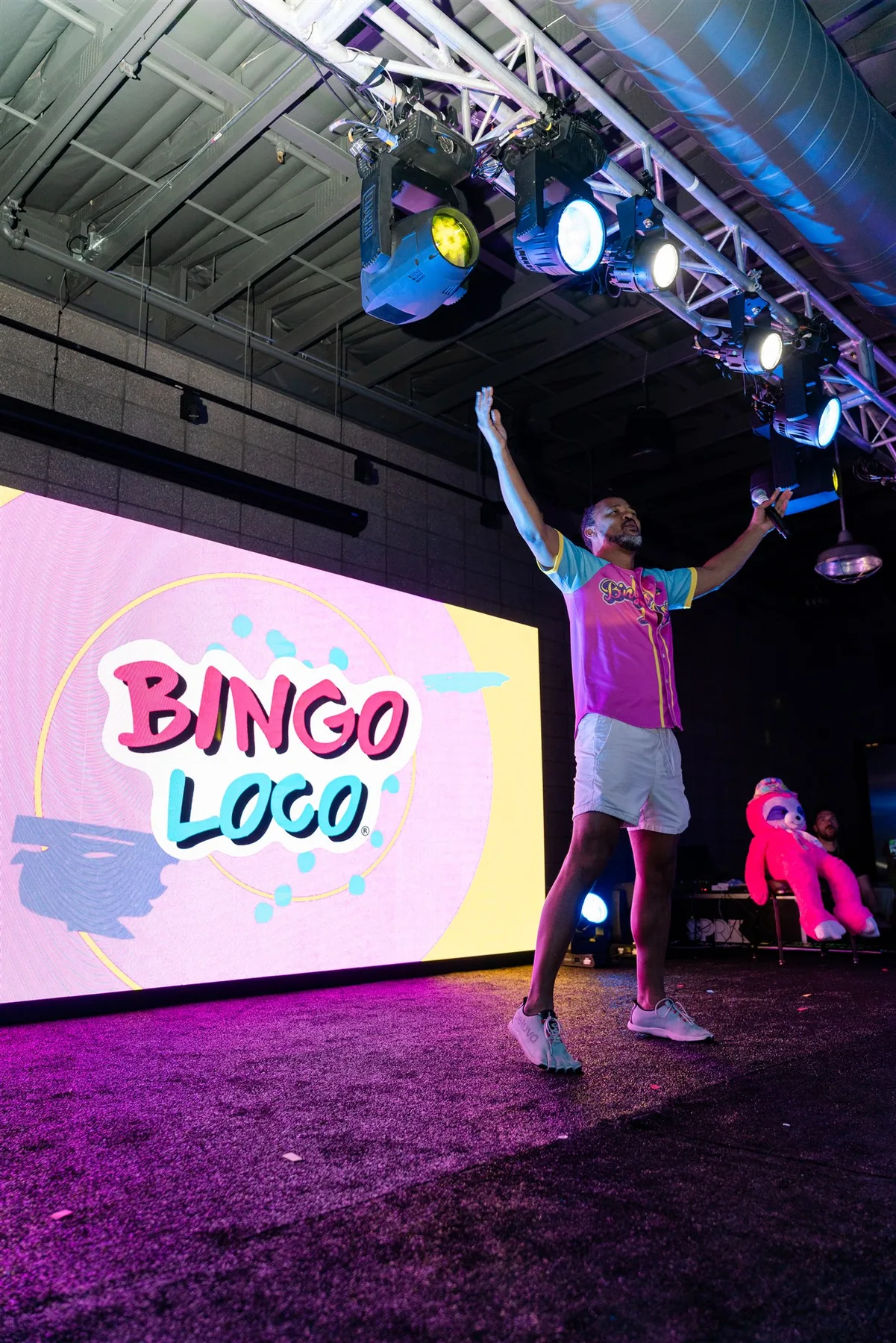 Event host onstage beside a large LED video wall during a live Bingo Loco production