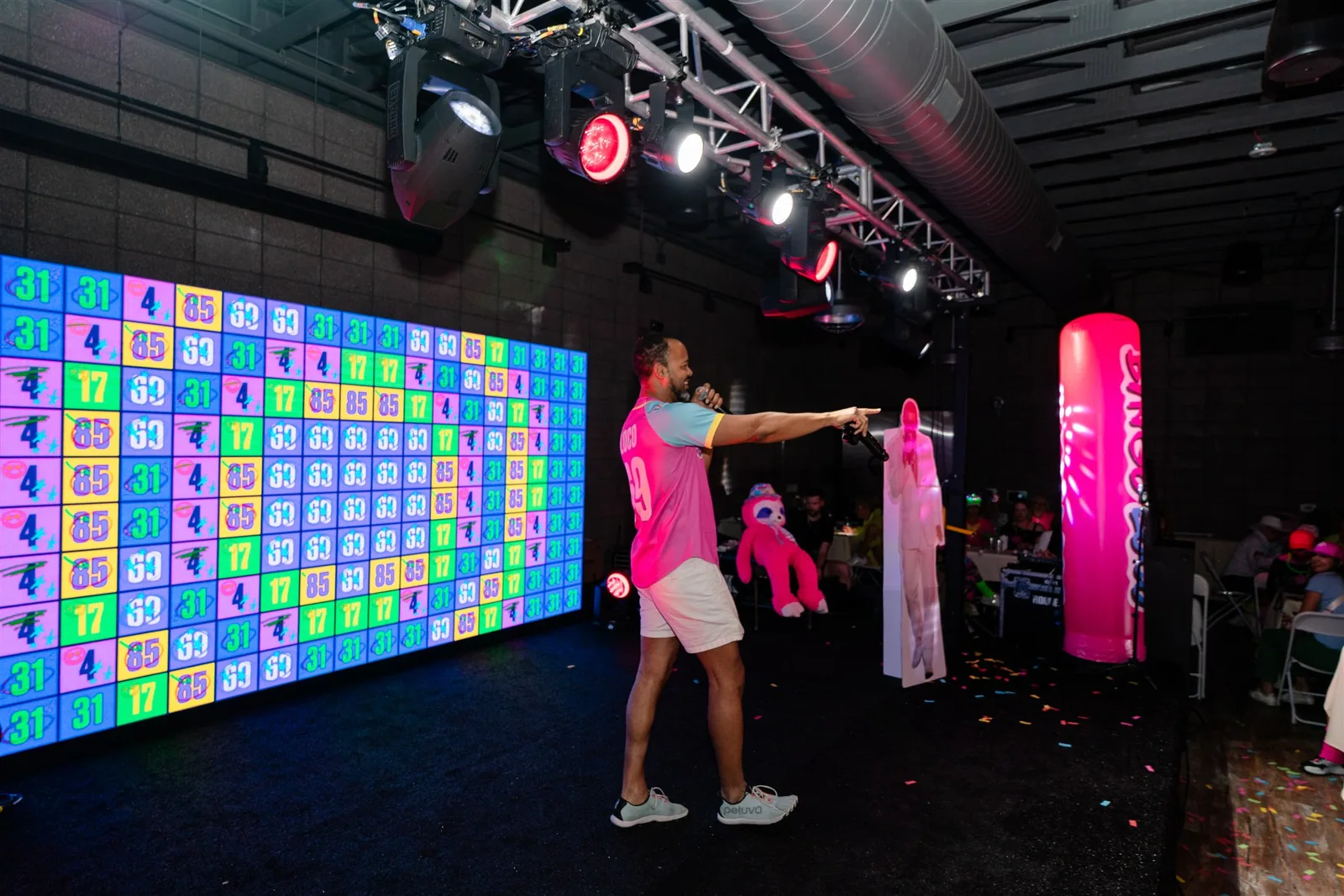 Event host presenting beside a colorful LED video wall during a live Bingo Loco show
